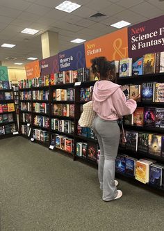 a woman looking at books in a library