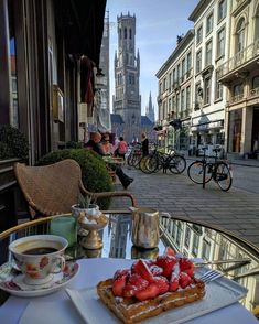 a table with food and drinks on it in front of some people walking down the street