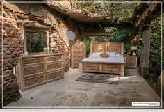 a bed and dressers in a room with brick walls, trees and plants on the ceiling