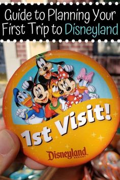 a person holding up a disneyland pin with the title guide to planning your first trip to disneyland