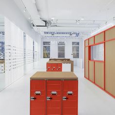 an empty room with many red cabinets and drawers on the wall, in front of several rows of eyeglasses