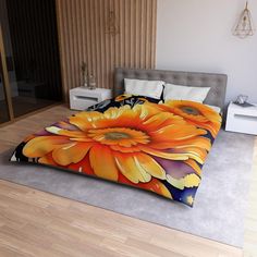 a bed with an orange flower on it in a room next to a wooden floor