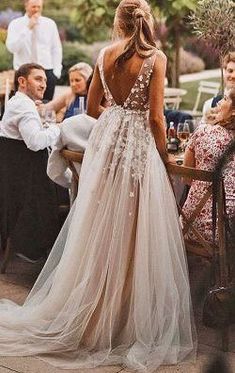 a woman in a long dress standing next to a table with people sitting around it