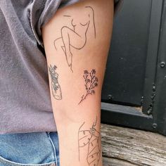 a woman's arm with tattoos on it and flowers in vases behind her