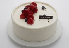 a white cake with raspberries and blueberries on top