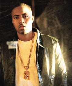 a man wearing a yellow shirt and black jacket with a gold chain on his neck