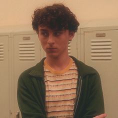 a young man standing in front of lockers with his arms crossed