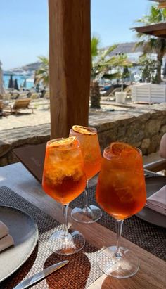 two glasses filled with drinks sitting on top of a table