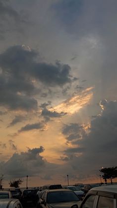 many cars parked in a parking lot under a cloudy sky