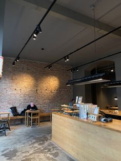 the interior of a restaurant with tables and chairs, lights hanging from the brick wall