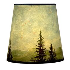 a lampshade with a painting of trees and mountains in the sky on it