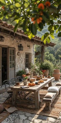 an outdoor dining table with chairs and benches on the outside patio, surrounded by greenery