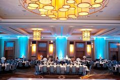 a banquet hall with tables and chairs set up for an event or function in front of a large chandelier