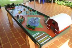 a child's play table with toy farm animals and cars on it in the middle of a room