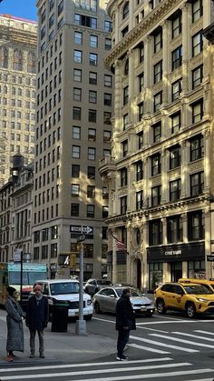 people are crossing the street in front of tall buildings