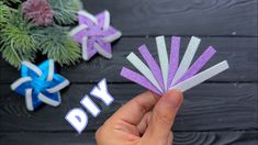 someone is holding up some purple and white paper stars with the word diy on them