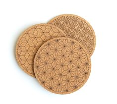 three circular cork coasters with intricate designs on them, set against a white background