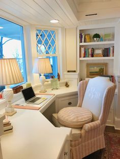 a desk with a laptop computer on it and a chair in front of the window