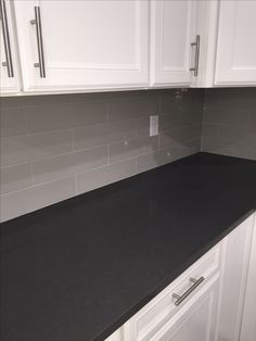 a black counter top in a kitchen with white cabinets and cupboards on either side