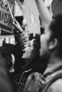 black and white photo of people holding signs in the air with one woman raising her hand