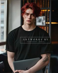 a man with red hair is holding a laptop and wearing a black t - shirt