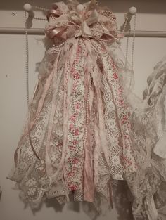 an old fashioned dress hanging on a clothes hanger with lace and ribbons attached to it