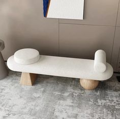 a white bench sitting in the middle of a room next to a vase and other items