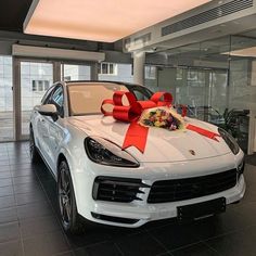 a white porsche cayen is decorated with red bows