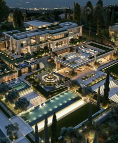 an aerial view of a mansion at night with lights shining on the building and pool area