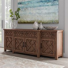 a wooden sideboard with two vases and a painting on the wall behind it