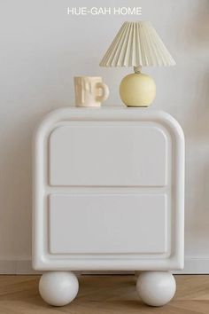 a white table with a lamp on top of it next to a vase and cup