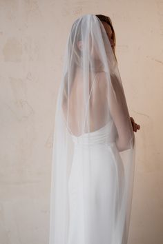 a woman in a white wedding dress with a veil on her head is looking back