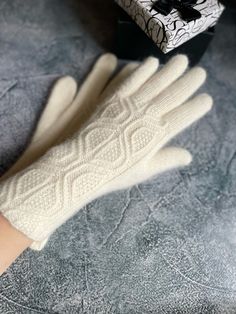 a pair of white gloves sitting on top of a bed next to a gift box