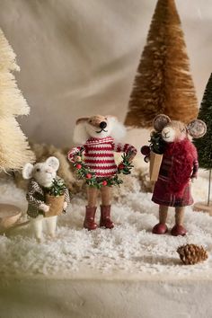 two figurines are standing in the snow next to christmas trees and pine cones