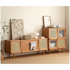 an entertainment center with wicker baskets and pictures on the top shelf, in front of a white wall