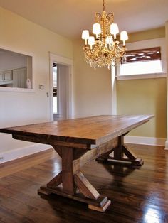 a large wooden table sitting in the middle of a room with hard wood flooring