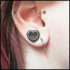 a woman wearing ear piercings with a heart shaped piece on it's side