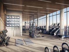 there are many exercise equipment in this large room with high ceilings and floor to ceiling windows