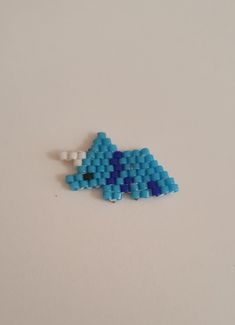 a blue beaded brooch sitting on top of a white table