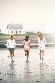 three girls running on the beach holding hands