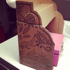 a cardboard box with an intricate design on the front and sides, sitting on a desk