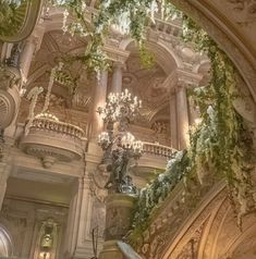 an ornate building with chandeliers and greenery hanging from the ceiling above it