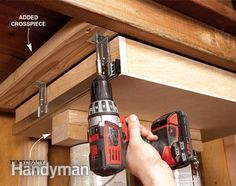 a man holding two drillers in his hand while working on the shelf above him