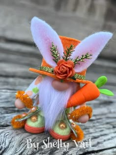 an orange and white stuffed rabbit with carrots on it's feet wearing a hat