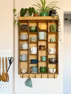 a wooden shelf filled with lots of cups and spoons next to a wall mounted planter