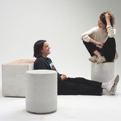 a man and woman sitting on concrete stools