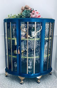 a blue cabinet with glass doors and gold trimmings on the bottom, decorated with flowers