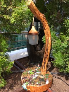 a wooden table with a lamp on top of it in the middle of some trees