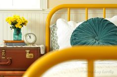 a bed with a yellow headboard and suitcases on the floor next to it