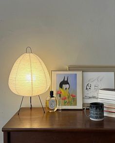 a lamp sitting on top of a wooden table next to pictures and a cup filled with coffee